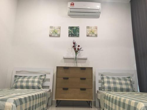 a bedroom with two beds and a dresser with a vase at Petaling Jaya Atria Sofo Suite in Petaling Jaya