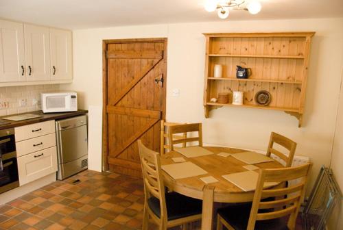 a kitchen with a wooden table with chairs and a microwave at Slieve Donard Cottage Widows Row cottages in Newcastle