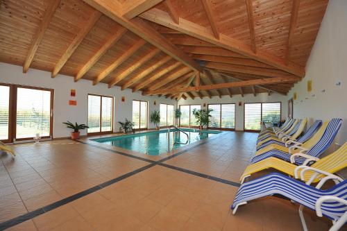 a swimming pool with lounge chairs in a building at Wellness Pension Waldhof in Sankt Georgen