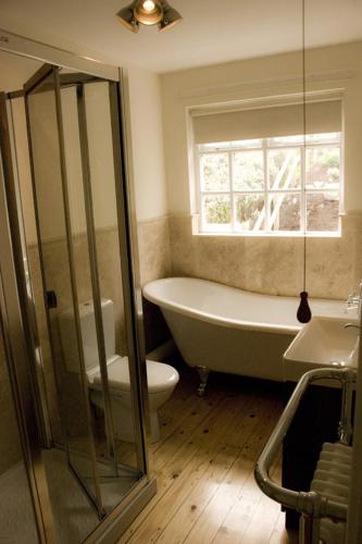 a bathroom with a tub and a toilet and a window at Slieve Donard Cottage Widows Row cottages in Newcastle