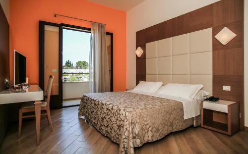 um quarto com uma cama, uma secretária e uma televisão em La Casarana Wellness Ecoresort em Lido Marini