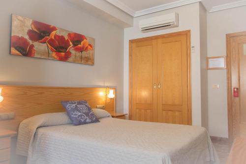 1 dormitorio con 1 cama y una pintura en la pared en L'Oncle Pere Habitacions, en L'Alcúdia