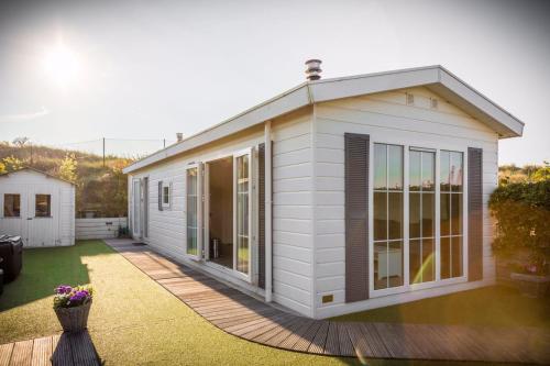 a small white house with glass doors on a yard at Zee en duin in IJmuiden