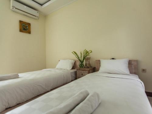 2 Betten in einem Zimmer mit weißer Bettwäsche in der Unterkunft Umah Bagus in Sanur