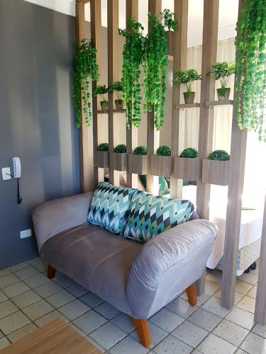 a couch sitting in a room with potted plants at Aconchegante Flat na Orla in Recife