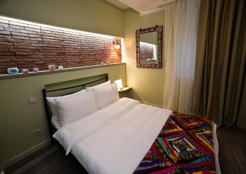 a bedroom with a white bed with a brick wall at No12 Boutique Hotel in Tbilisi City
