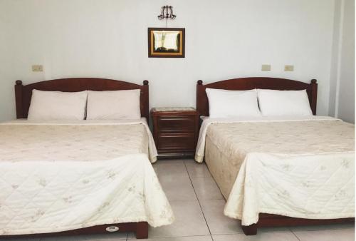 a bedroom with two beds and a picture on the wall at Dennis Manor in Toucheng