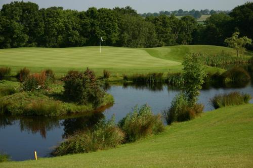 a golf course with a pond next to a green at Woodbury Park Hotel & Spa in Exeter