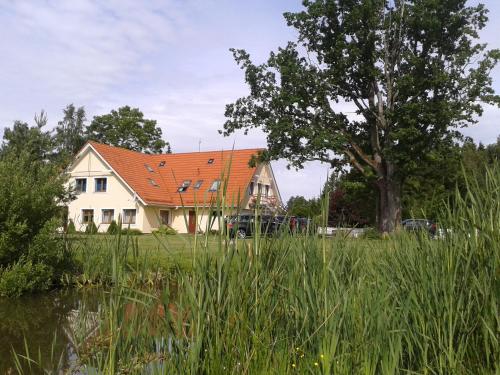 una casa con techo rojo y un árbol en Villa River Rose en Jõesuu