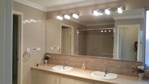 uma casa de banho com 2 lavatórios e um espelho grande em Vimal's Homestay em Perth