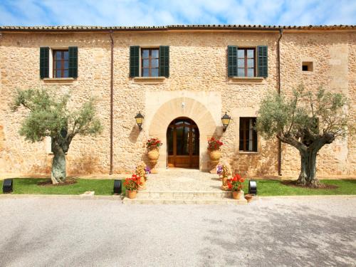 a large stone building with a door and two trees at Puig de Ros d’Alt in Llucmajor