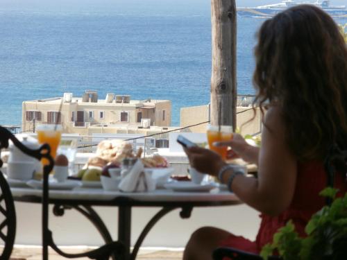 a woman sitting at a table looking out at the ocean at Galini Bungalows in Kionia