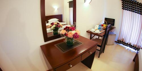 a room with a wooden dresser with flowers on it at Hotel Shanelo in Negombo