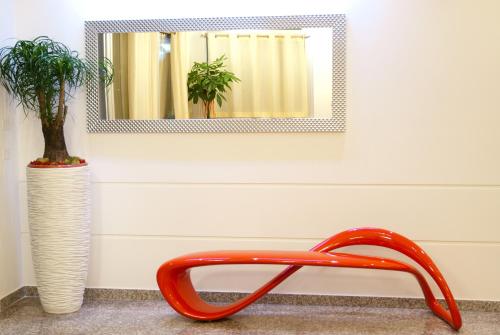 a mirror and a red chair next to a vase at Hotel Ristorante Cesare in Savignano sul Rubicone