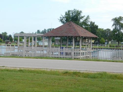a wooden gazebo with a white fence next to a road at AmericInn by Wyndham Oscoda Near AuSable River in Oscoda