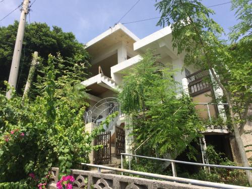 a white house with a balcony and trees at Body Balance House in Miyako Island