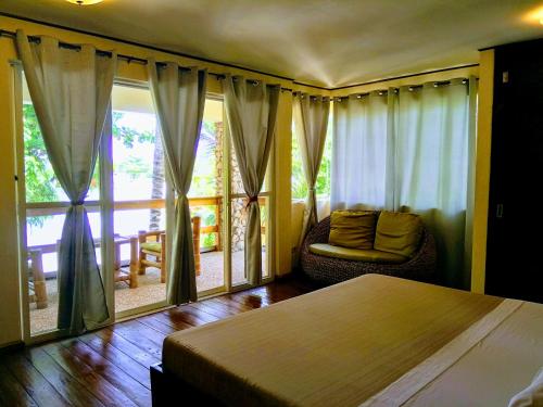 a bedroom with a bed and a chair and a window at Angelina Beach Resort & Italian Restaurant Malapascua in Malapascua Island