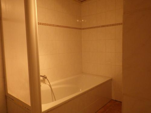 a bath tub in a bathroom with white tiles at Ferienwohnung Kremer in Bad Münstereifel