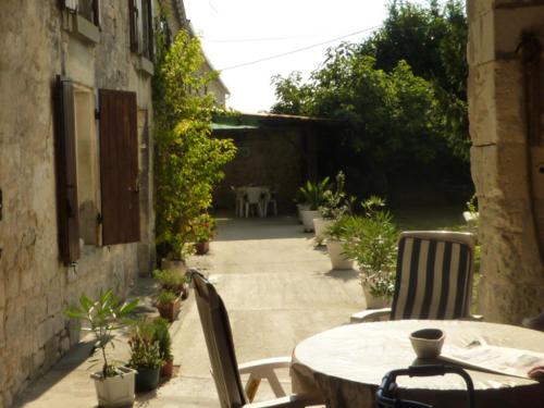un patio al aire libre con mesa, sillas y plantas en la Belle Charentaise, en Mainxe
