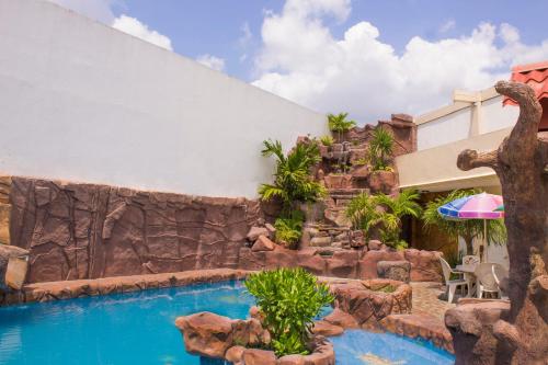 un complexe avec une piscine et un mur de roche dans l'établissement Hotel San Rafael, à Poza Rica de Hidalgo