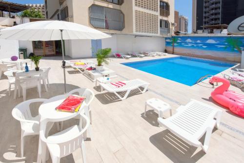 a pool with tables and chairs and a pink flamingo float at My Pretty Payma Apartamentos in Benidorm