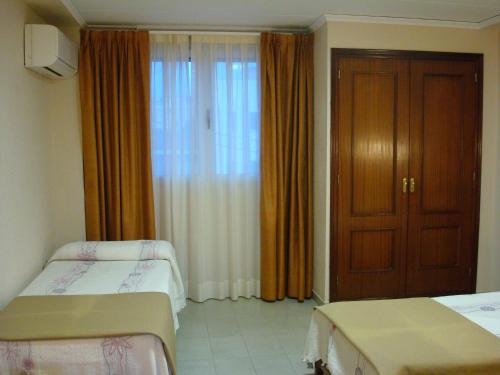 ガンディアにあるHotel Fin De Semanaのベッド2台とドアが備わるホテルルームです。