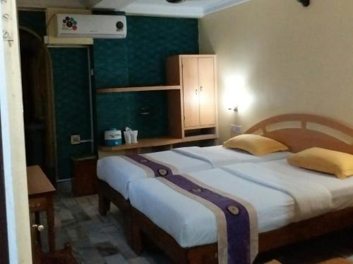 two beds in a room with green walls at Hotel Mahalaxmi Indo Myanmar in Guwahati