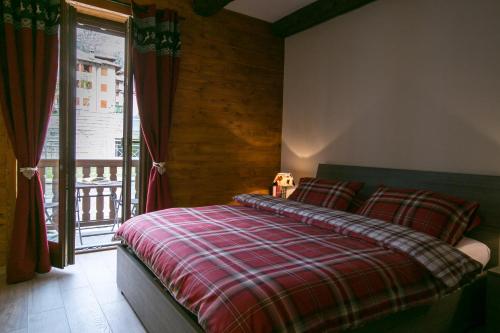 ein Schlafzimmer mit einem Bett mit einer roten karierten Decke in der Unterkunft Appartamento Monte Bianco in La Salle