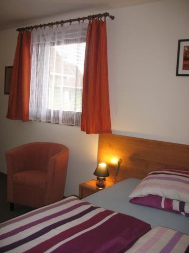 a bedroom with a bed and a chair and a window at Penzion Pod Vápenkami in Strážnice
