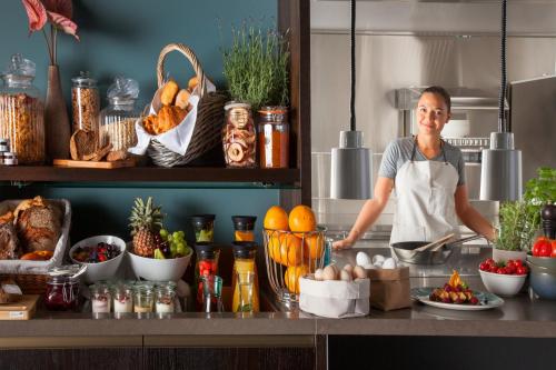 a woman standing in a kitchen preparing food at Acasa Suites Zurich Oerlikon in Zürich