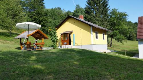a small yellow house with an umbrella in the yard at Ferienhaus Dreiländereck in Minihof Liebau