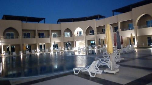 a large building with white chairs and a pool at Gewan Hotel Cairo in Cairo