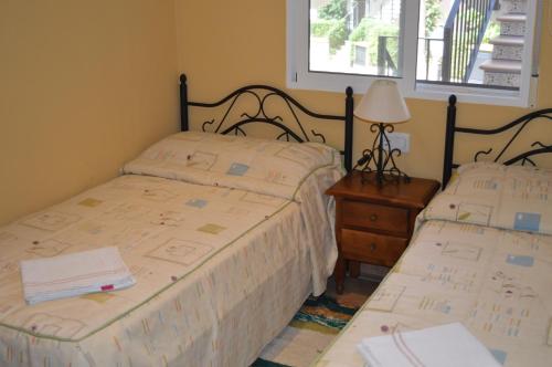 ベラにあるAl-andalus Residencialのベッドルーム1室(ベッド2台、ランプ、窓付)