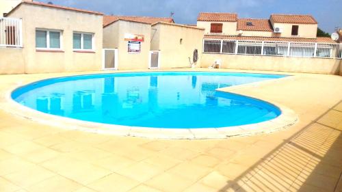 une piscine avec de l'eau bleue devant un immeuble dans l'établissement Lagon 173 - Maison de Vacances - 3 Chambres, à Gruissan