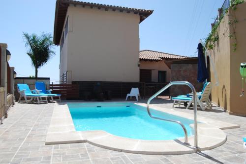 a swimming pool in a patio with blue chairs at Villa El Tagoro in Candelaria