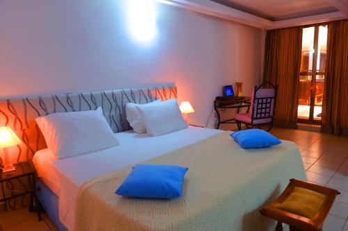 a bedroom with a large bed with blue pillows at Résidence Théresia in Lomé