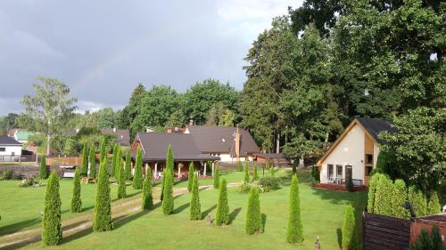 a garden with trees and a house in the background at Forest Edge Lodge in Rīga
