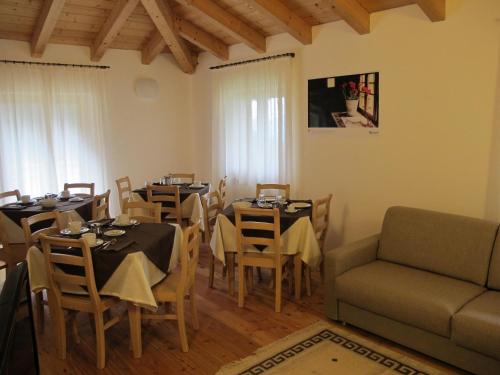 a dining room with tables and chairs and a couch at Il Cardo Trentino in Bedollo