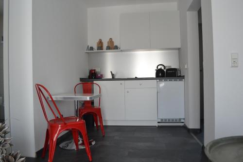 a small kitchen with red chairs and a table at Walnusshof Bad Salzungen in Bad Salzungen