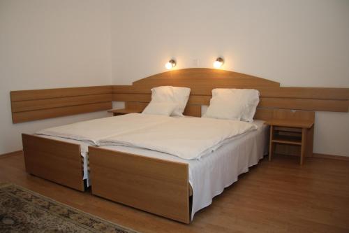 a bedroom with a large bed with a wooden headboard at Bagoly Fogadó in Gyömrő
