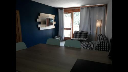 レ・デュー・アルプにあるRésidence le Plein Sudの青い壁の客室で、テーブルと椅子が備わります。