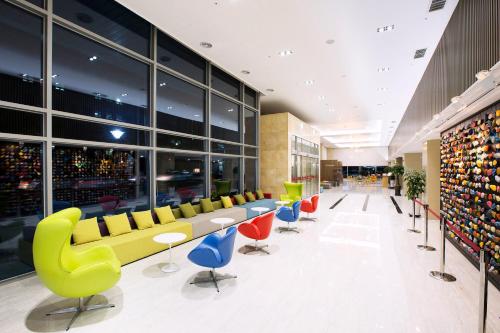 a lobby with colorful chairs and tables in a building at Ramada by Wyndham Jeju City Hall in Jeju