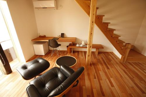 a living room with black leather chairs and a table at Yamagata The Takinami in Nanyo