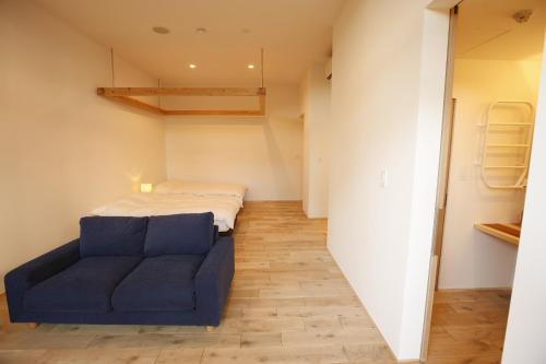 a small bedroom with a bed and a blue couch at Yamagata The Takinami in Nanyo