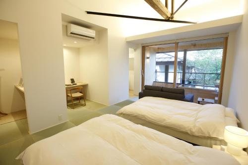 a bedroom with two beds and a chair and a window at Yamagata The Takinami in Nanyo