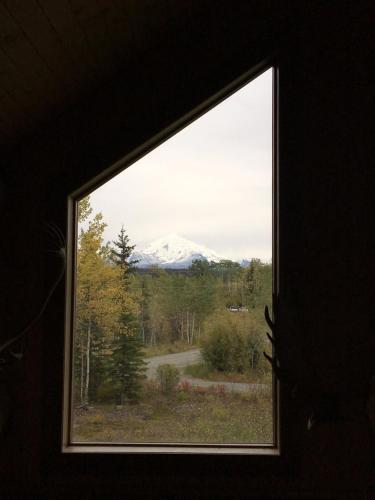 a view of a snow covered mountain through a window at Sawing Logzz Cabin in Copper Center