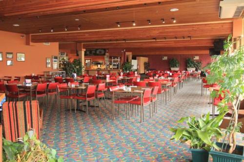 a restaurant with tables and chairs and red chairs at Rubicon Hotel Motel in Eildon