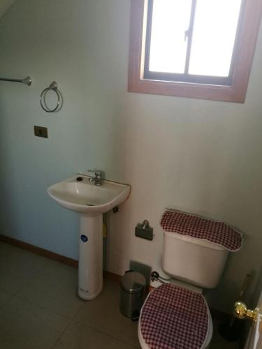 a bathroom with a sink and a toilet and a window at Casa Rukalma Estación in Villarrica