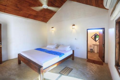 a bedroom with a bed with a wooden ceiling at Paper Moon Kudils in Arugam Bay