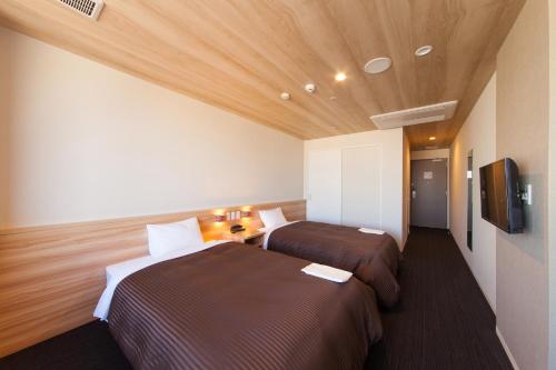 a hotel room with two beds and a flat screen tv at Izumisano Center Hotel Kansai International Airport in Izumi-Sano